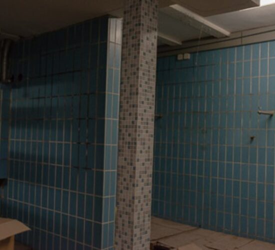 Foto eines alten leeren Raumes mit blauen Fliesen an der Wand im Stil der sechziger Jahre