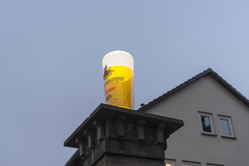 Nahaufnahme eines riesiges Bierglases auf einem Pfeiler des Eingangs zum Gewerbepark Alte Brauerei
