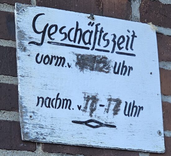 Schild mit den ehemaligen Geschäftszeiten am Gebäude der alten Wassermühle im Gewerbepark Alte Brauerei